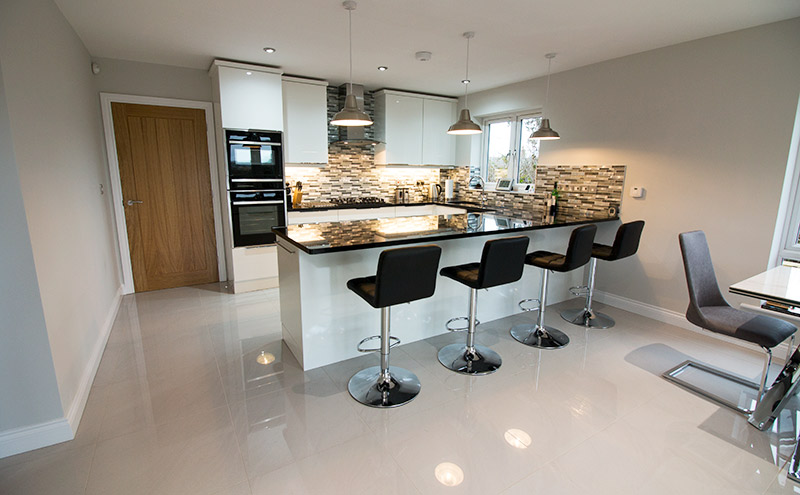 Large modern kitchen featuring high gloss floor tiles with stone and glass mosaics from UK Tiles Direct