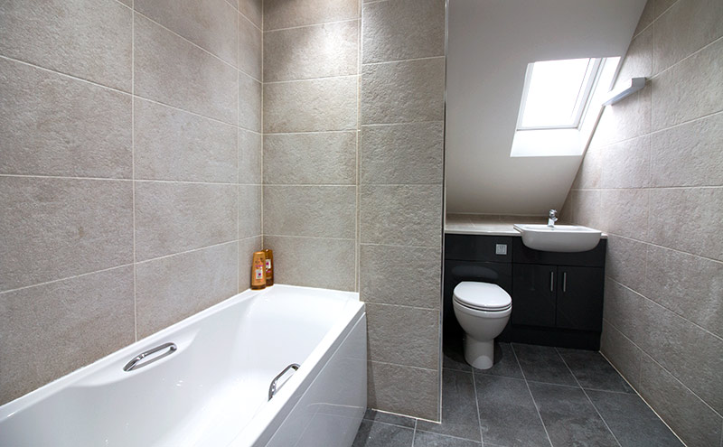 This modern family bathroom features Stoneway Black stone-effect porcelain floor tiles with contrasting Ivory wall tiles 