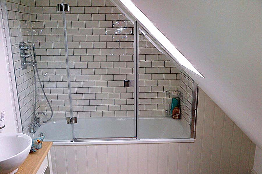 This stylish bespoke angled over bath shower screen and period subway tiles give a traditional twist to the cool over bath shower