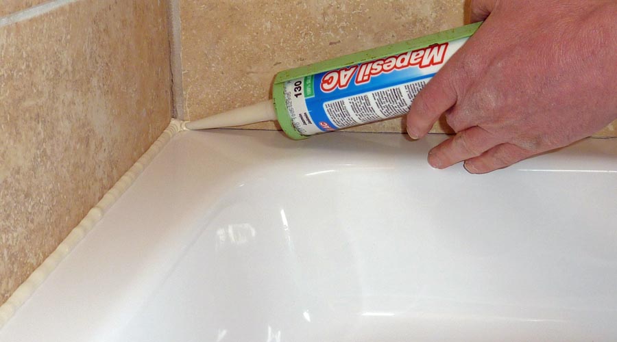 Working from the corner of the shower tray an application gun is used to apply the silicone sealant