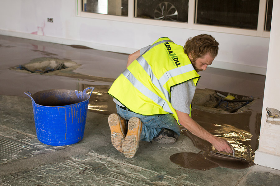 A UK Tiles Direct tiler expertly leveling the floor of a car showroom in Dorset ready for fixing porcelain floor tiles